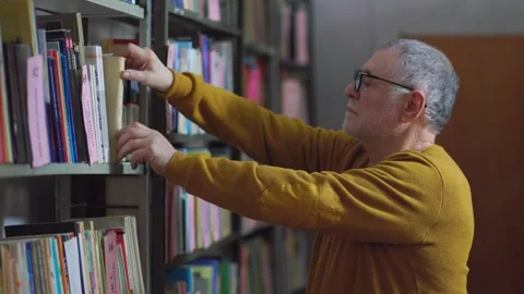 The Discerning Reader A Senior Man Selecting a Book in the Library Stock Footage 274288281