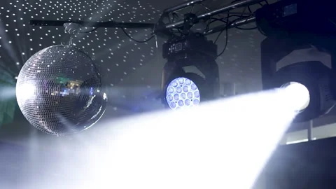 Disco ball with bright rays under the ceiling, night party. Stockbeeldmateriaal 169800341