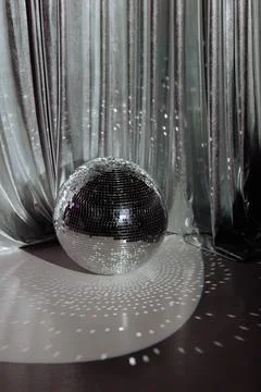 Disco ball casting light, silvery curtain backdrop. Stock Photos