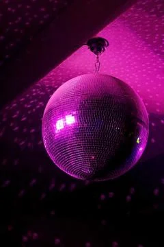 Disco ball in motion reflecting pink light in night club with copy-space Stock Photos