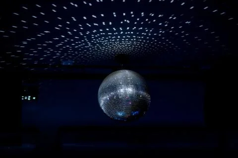 Disco ball reflecting light patterns on dark ceiling in nightclub Stock Photos