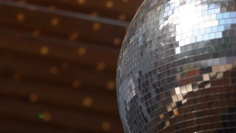 Disco ball spinning on the street casts glare from sunlight onto a wooden wall Stock Footage 128237291