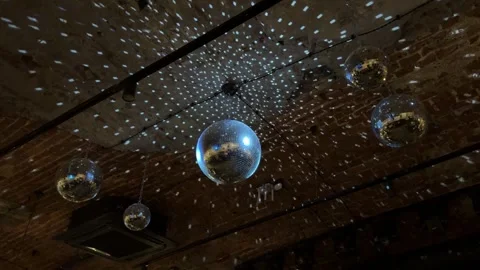 Disco ball spins on ceiling, illuminating dark space with its rays. Dance Stockbeeldmateriaal 322052558
