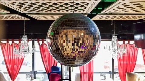 A disco ball is suspended from the ceiling inside a cafe or restaurant. Resta Stock Photos
