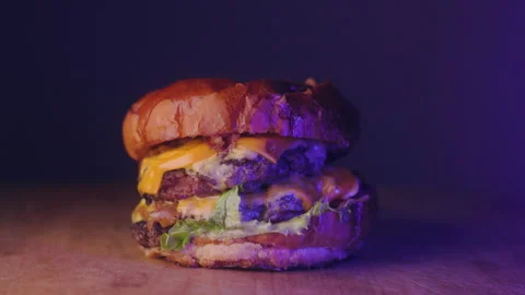 Disco Light and Grilled Beef Burger with Melted Cheese and Fresh Vegetables on a Stock Footage 236575837