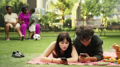 Disconnected couple scrolling through social media laying on picnic blanket Stock Footage 341411511