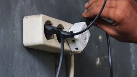 Disconnecting multiple electrical plugs from a wall outlet Stock Footage 337446327
