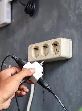 Disconnecting multiple electrical plugs from a wall outlet Stock Photos