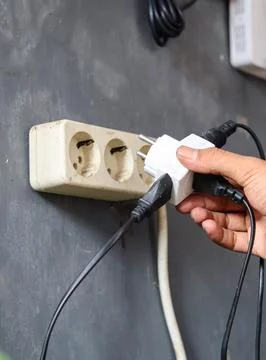 Disconnecting multiple electrical plugs from a wall outlet Stock Photos