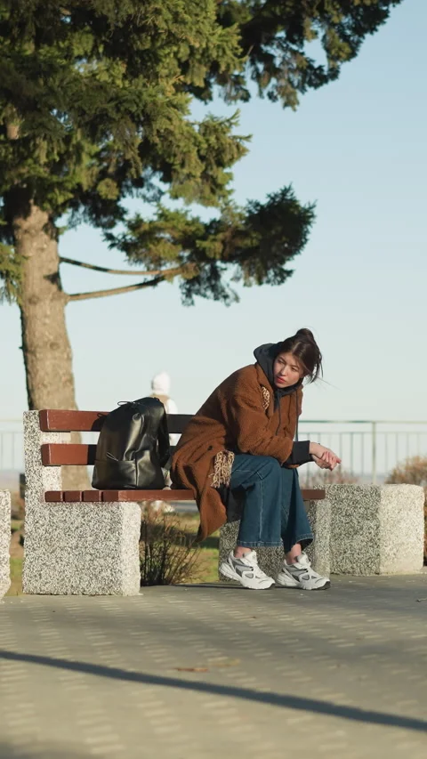 Disconsolate Girl Sitting Alone on Bench in Urban Park with Somber Expression Vídeos de archivo 309718511
