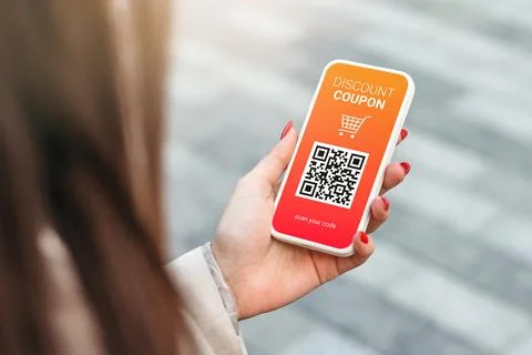 Discount coupon with QR code on smartphone in a female hand on a green grass Foto stock
