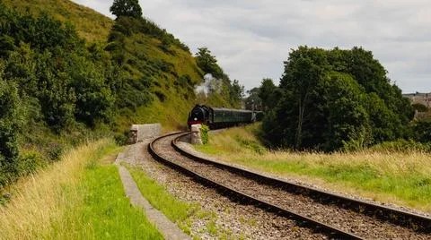 Discover a captivating steam engine moving along a scenic railway track Stock Photos