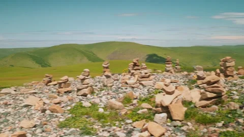 Discovering ancient stone piles in a vast green landscape during a sunny day at Stock Footage 313107245