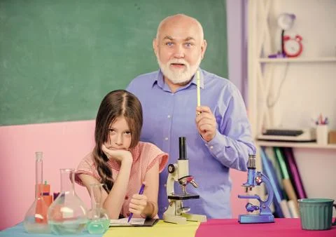 Discovering cure. science classroom. small girl with man tutor study chemistry Foto stock