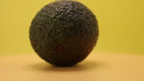 Discovering the unique texture and color of a  avocado on a bright yellow backgr Stock Footage 328635041