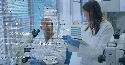 Discussing hologram data two scientists wearing white lab coats at lab bench, Stock Photos
