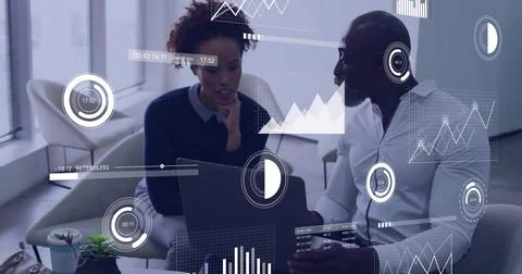 Discussing pair reviewing data in lounge with laptop overlays, white shirt dark Stock Photos