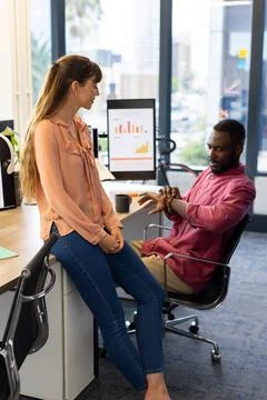 Discussing project, colleagues in office with computer displaying charts and Stock Photos