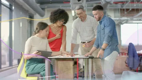 Discussing team leaning over round table in open-plan office, woman in red top Stock Footage 332882019
