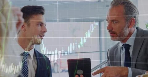 Discussing two men pointing at device and referencing candlestick chart in Foto stock