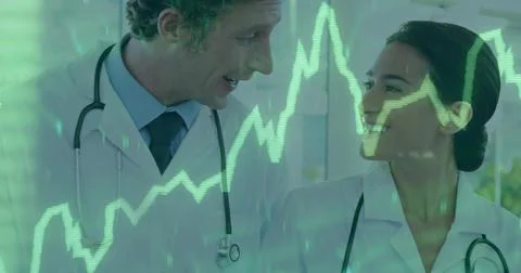 Discussing two physicians exchanging data in clinic room, wearing lab coats and Stock Photos