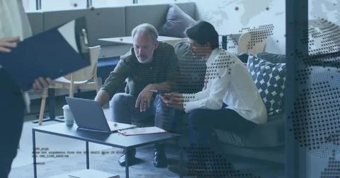 Discussing two seated men in white shirt pointing at laptop on lounge sofa, w Stock Photos