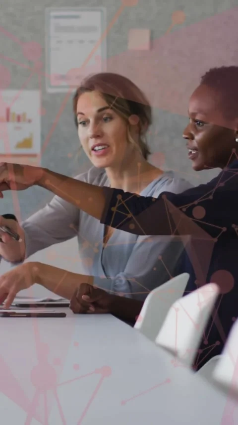 Discussing work with data visualization overlay, two women in office setting Stock Footage 319883326