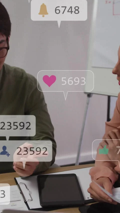 Discussing work, two colleagues in office with animation of social media Stock Footage 344370329