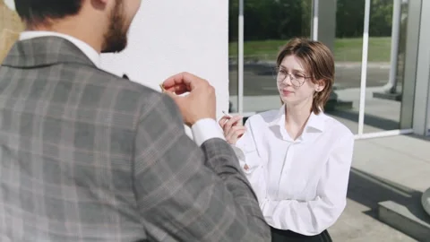 Discussion between two smoking professionals outside a modern office building on Video stock 312903029
