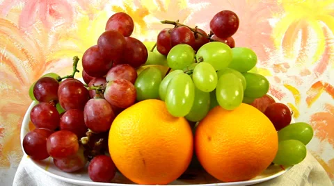 Dish with apples, grapes and oranges on abstract colored background, still life Stock Footage 36400479