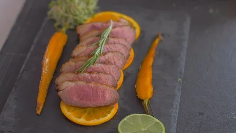 A dish of duck breasts on an orange sofa. Well-baked duck. Video stock 110024301