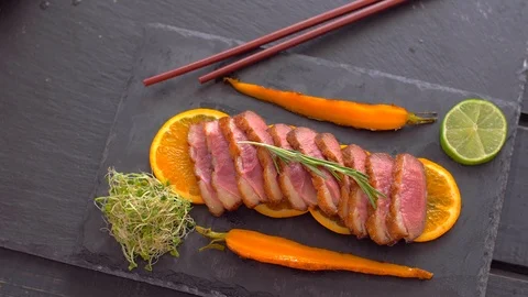 A dish of duck breasts on an orange sofa. Well-baked duck. Video stock 110026538