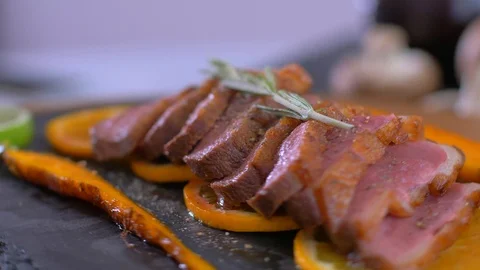 A dish of duck breasts on an orange sofa. Well-baked duck. Video stock 110033306