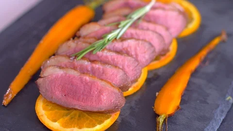 A dish of duck breasts on an orange sofa. Well-baked duck. Video stock 110036414