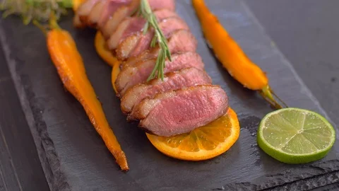 A dish of duck breasts on an orange sofa. Well-baked duck. Video stock 110041857