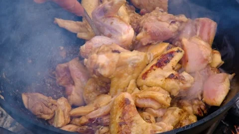 A dish on a fire in a cauldron. The meat is stewed in a cauldron. Chicken meat Stock Footage 278463128