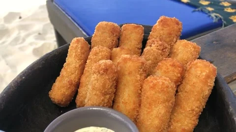 Dish of fishfingers with sauce dip on a table at beach Stock Footage 176008237
