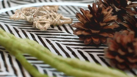 Dish with herringbone pattern, straw star, conifer cones and green wool yarn. 4K Stock Footage 98290994