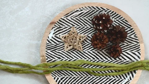 Dish with herringbone pattern, straw star, conifer cones and green wool yarn. 4K Stock Footage 98291016