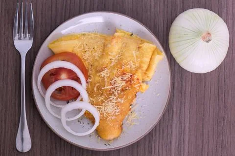 Dish of omelette with parmesan cheese, a fork and an onion Stock Photos