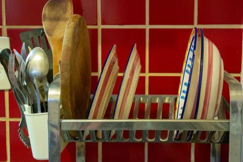 A dish rack with drying plates and cooking utensils Foto stock