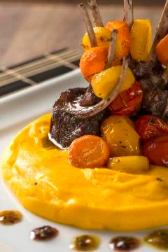 A dish of Rack of Lamb with mashed cassava and a glass of wine on the table. Stock Photos