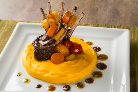 A dish of Rack of Lamb with mashed cassava and a glass of wine on the table. Stock Photos