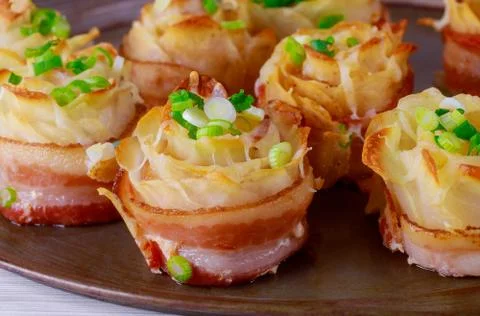 Dish of roasted potatoes with roll bacon and cheese, onions Stock Photos