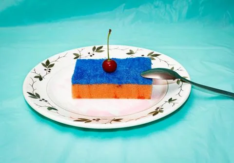 A dish sponge is placed on a plate in the form of a cake with a real cherry o Stock Photos