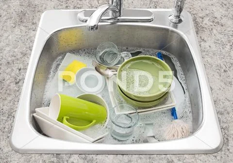 Dishes soaking in the kitchen sink Stock Photos