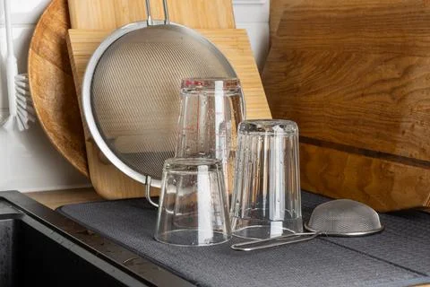 Dishes stacked on drying mat with kitchen tools nearby, ready to be washed. Foto stock
