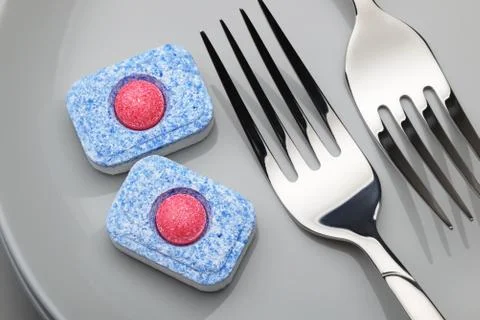 Dishwasher detergent tablet and fork Stock Photos