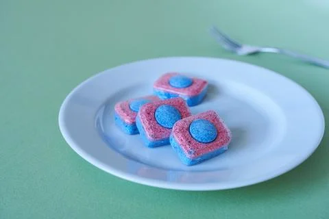 Dishwasher detergent in tablet form with clean dishes. Shallow focus Stock Photos