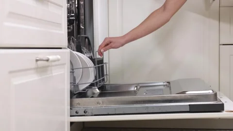 Dishwasher loading process with clean plates and utensils being organized into Stock Footage 324308542